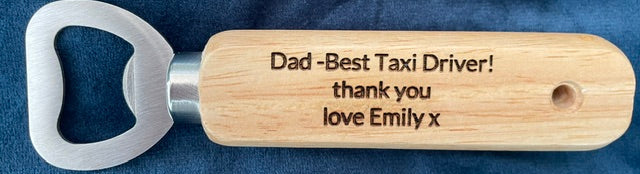 Wooden bottle opener with engraved message on a blue fabric background