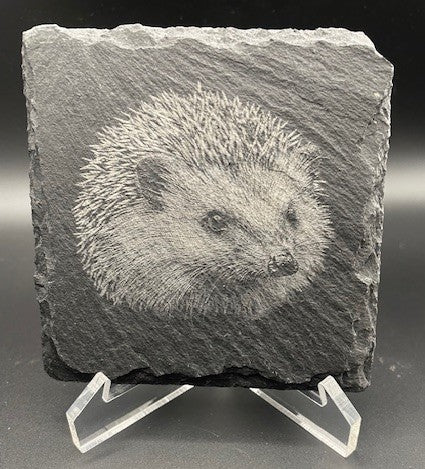 Carved hedgehog on a slate stone with a stand against a black background