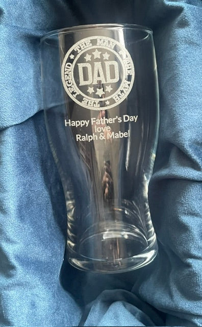 Clear glass with 'DAD' engraving on a blue fabric background