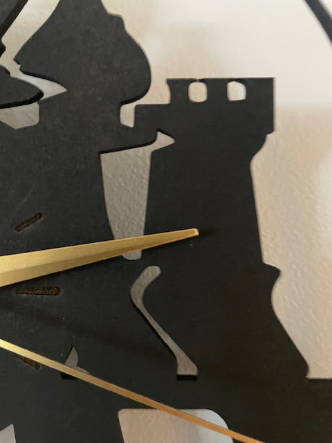 Close-up of a clock with black horse silhouette and gold hands on a white background