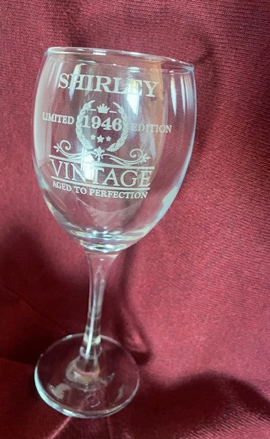 Wine glass with engraved text on a red fabric background