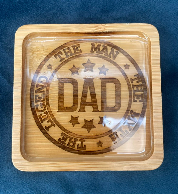 Wooden tray with engraved 'DAD' and decorative text on a blue background