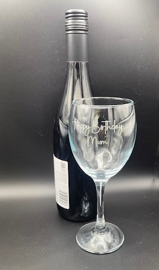 Wine bottle and glass with 'Happy Birthday Mum' engraving on a dark background