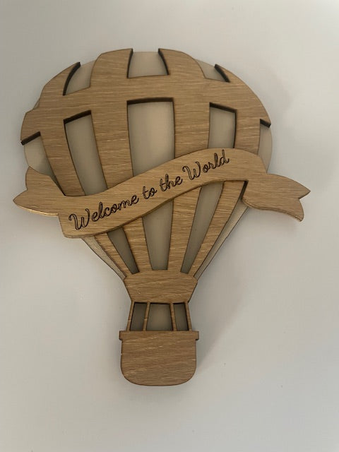 Wooden baby rattle with 'Welcome to the World' engraving on a white background