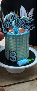 Light blue birthday cake with 'Official Teenager' and number '13' on a white plate.