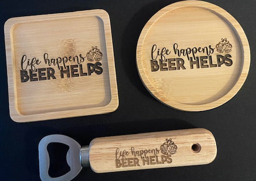 Wooden coasters, bottle opener, and keychain with 'life happens, BEER HELPS' text on a black surface.