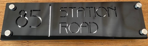 Metal sign with '85 Station Road' on a wooden background