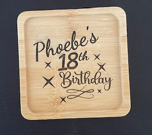 Wooden coaster with 'Phoebe's 18th Birthday' engraving on a black surface