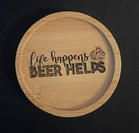 Wooden coaster with 'Life happens, Beer helps' text on a black surface