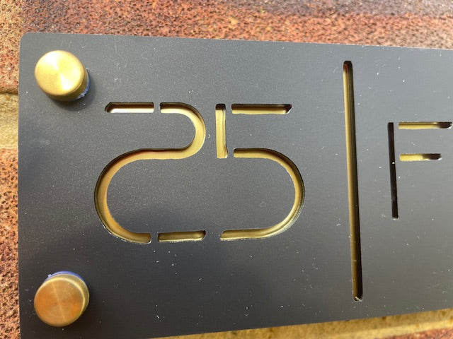 Metallic plaque with '25F' engraving on a textured surface