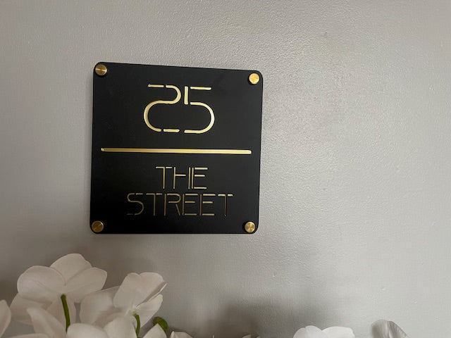 Black and gold sign with '25' and 'The Street' on a gray wall.