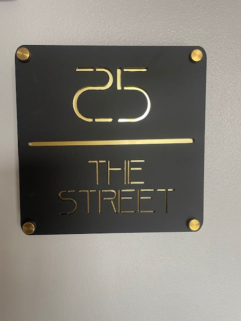 Black sign with gold text and numbers on a gray background