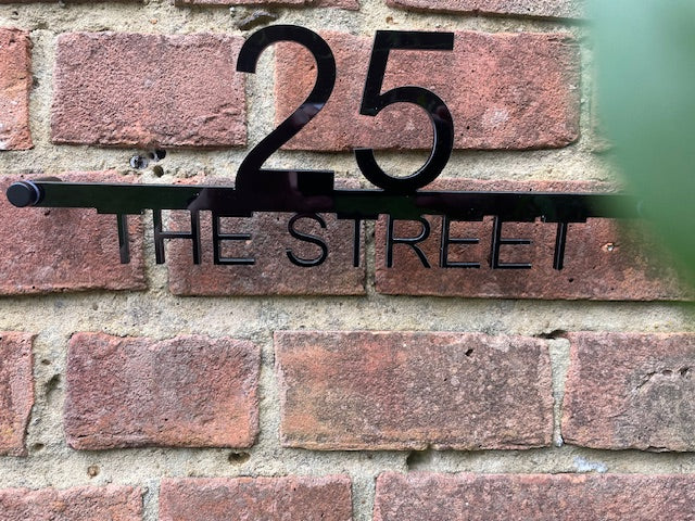 House number '25' and street name 'THE STREET' on a brick wall.