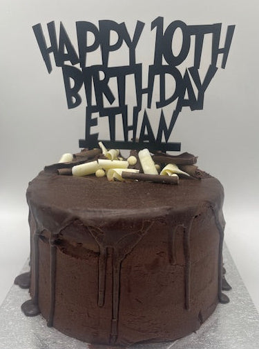 Chocolate cake with 'Happy 10th Birthday Ethan' topper on a white background