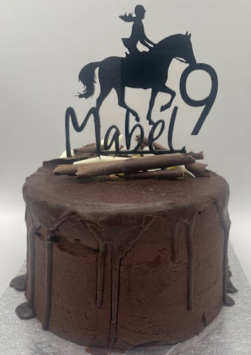 Chocolate cake with horse and rider topper on a gray background