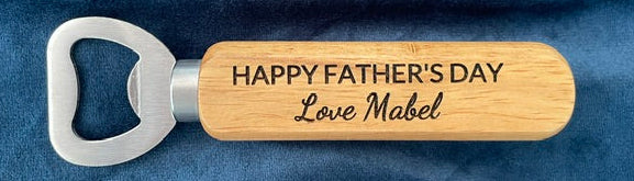 Wooden bottle opener with 'Happy Father's Day' text on a blue fabric background